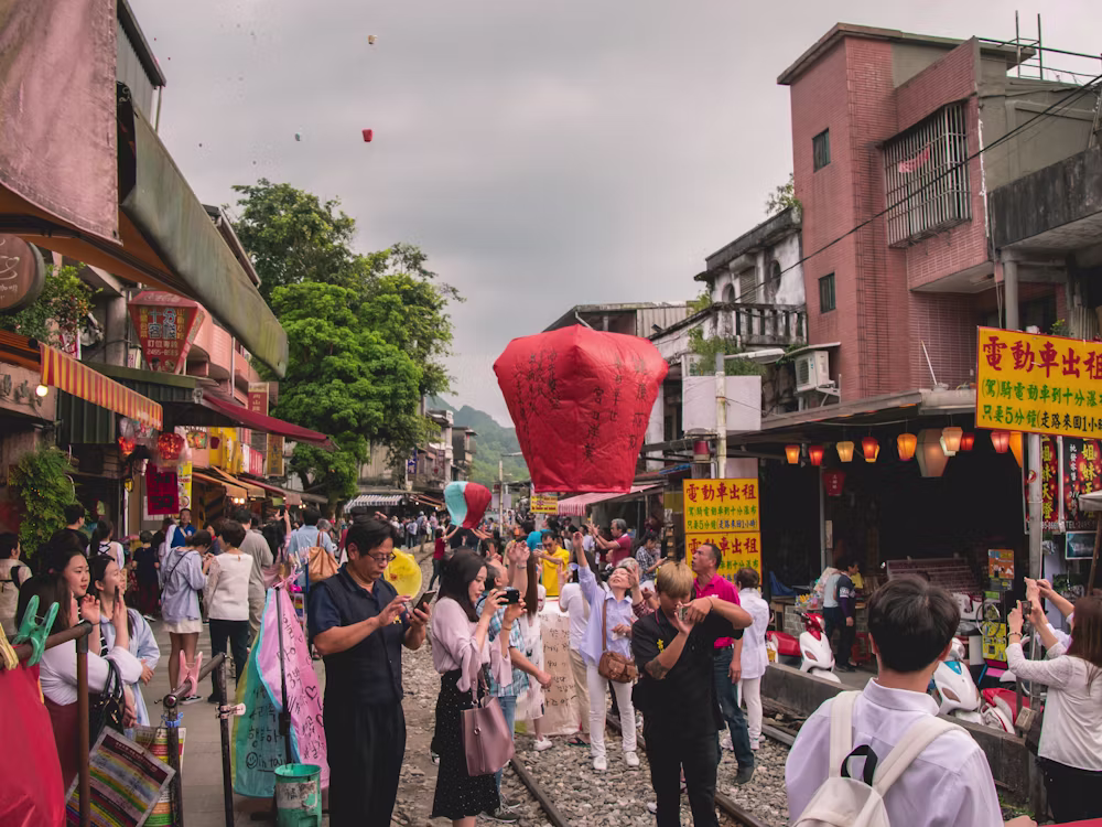 Young people releasing a glowing sky lantern in a lively Taiwan street town